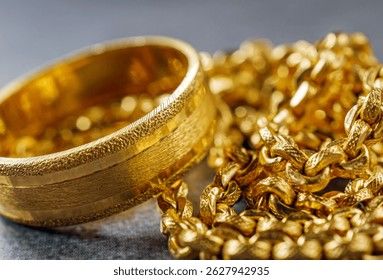 En bred guldring och en glittrande guldkedja i en närbild.